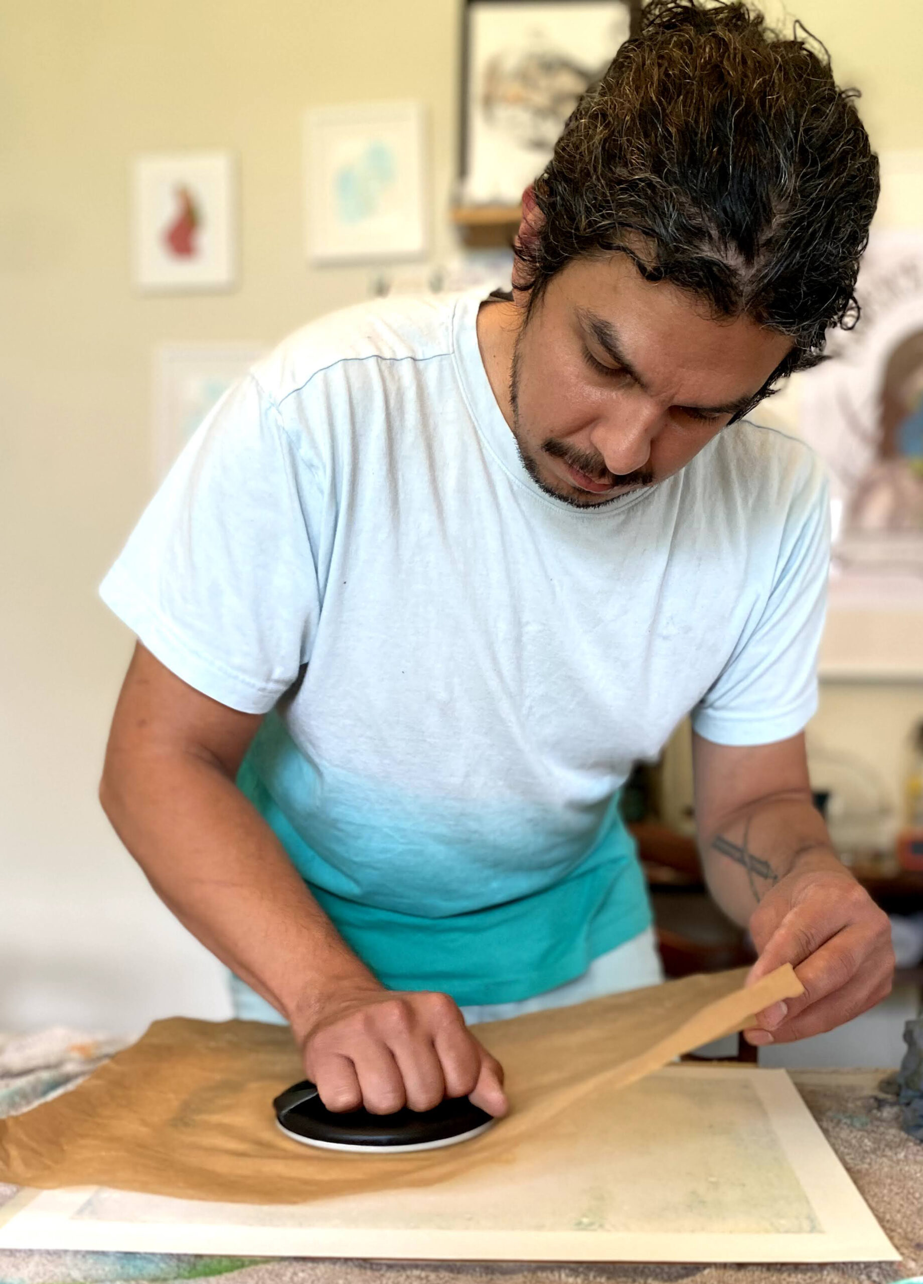 Matthew Willie Garcia, photo of the artist hand printing a wood block print