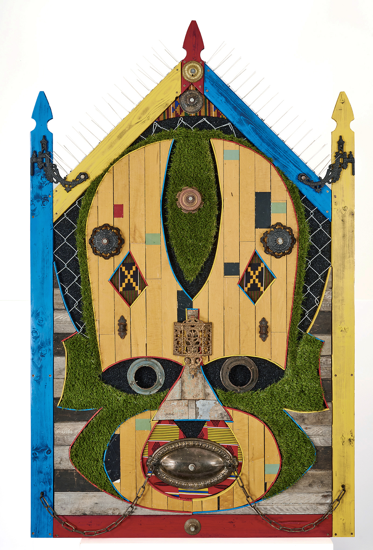 Sentinel, The Guardian; by Aaron Coleman. A mixed media assemblage evoking Ghanaian masks, made from fencing, fake turf, and salvaged wood from a neighbor's home lost to gentrification.
