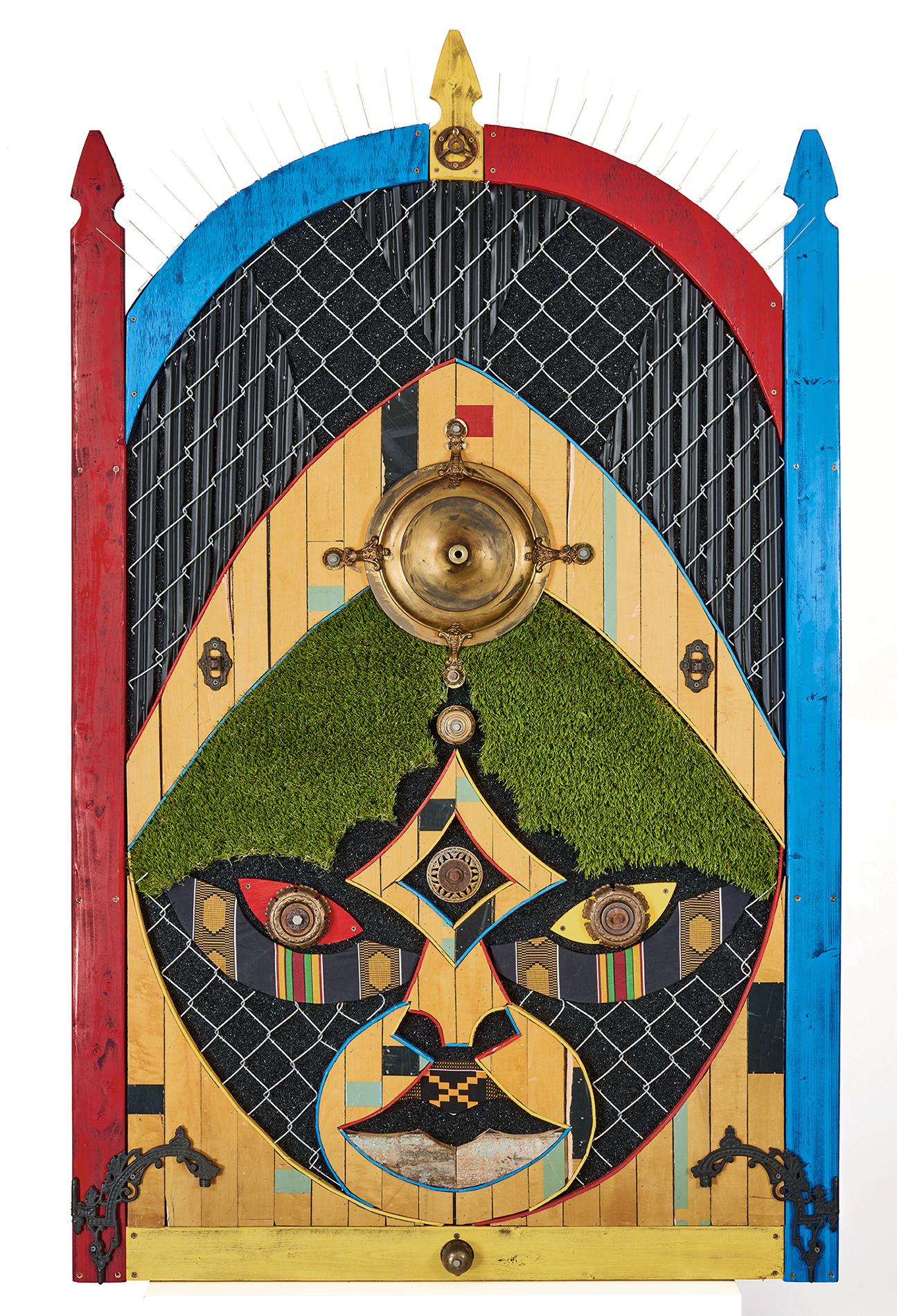 Sentinel, The Gatekeeper; by Aaron Coleman. A mixed media assemblage evoking Ghanaian masks, made from fencing, fake turf, and salvaged wood from a neighbor's home lost to gentrification.