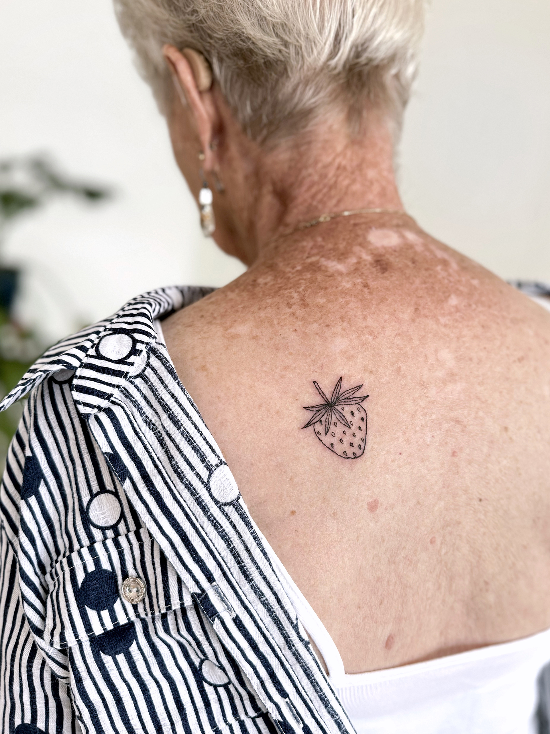 A line drawing of a strawberry is tattooed on the left shoulder of the artist's great grandmother.