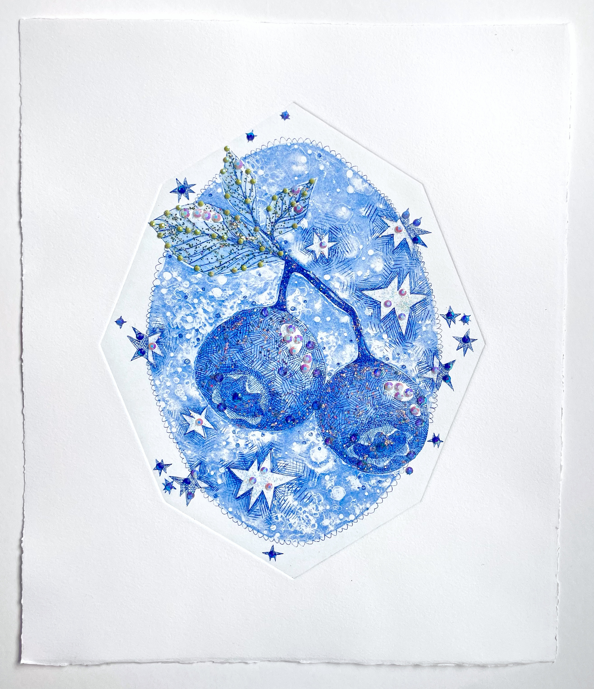 A pair of blue pomegranates are composed of intricate line work reminiscent of embroidery, accented with plastic jewels.