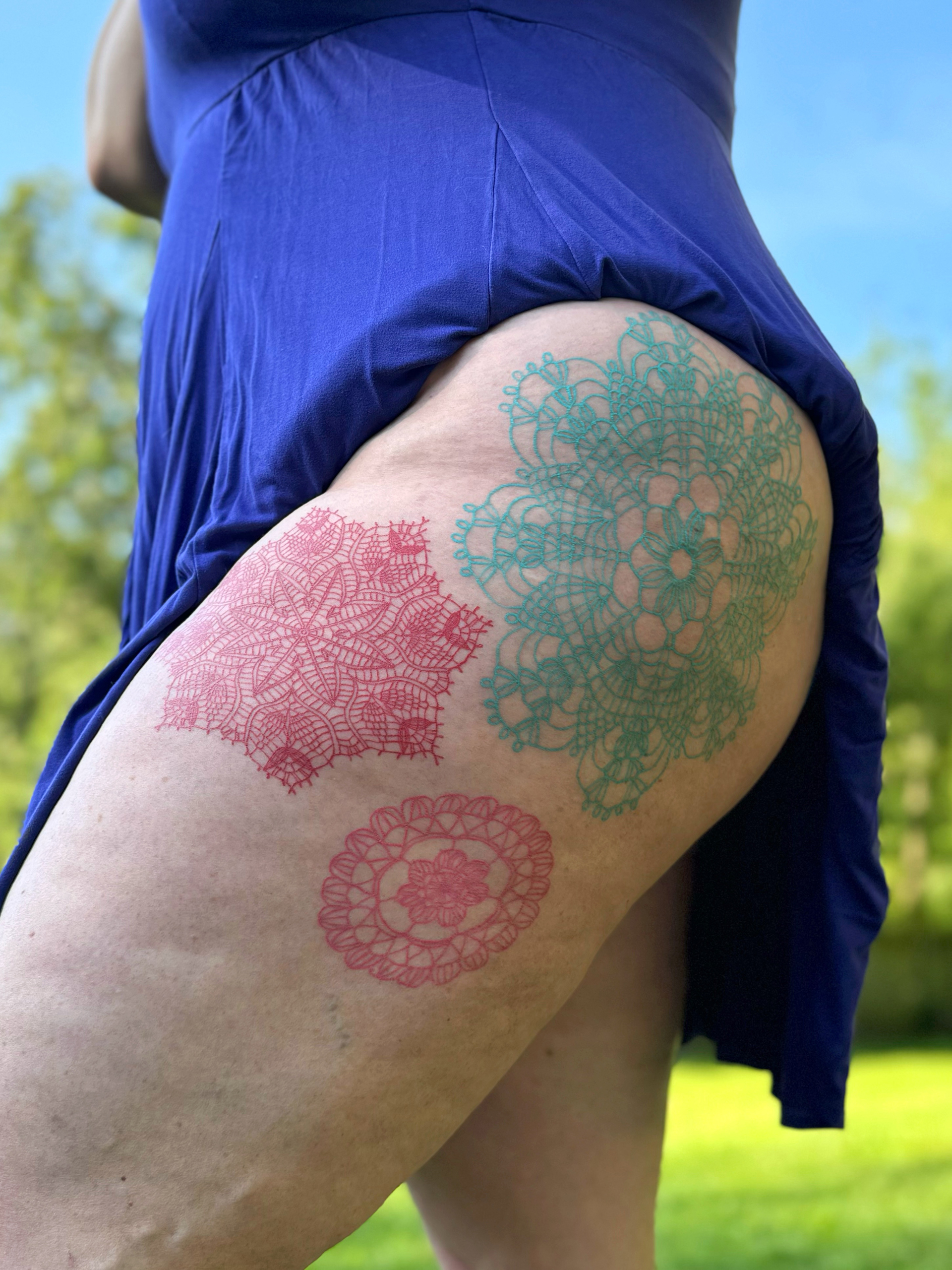 Red and teal tattooed doilies cover the upper thigh of the artist's mother