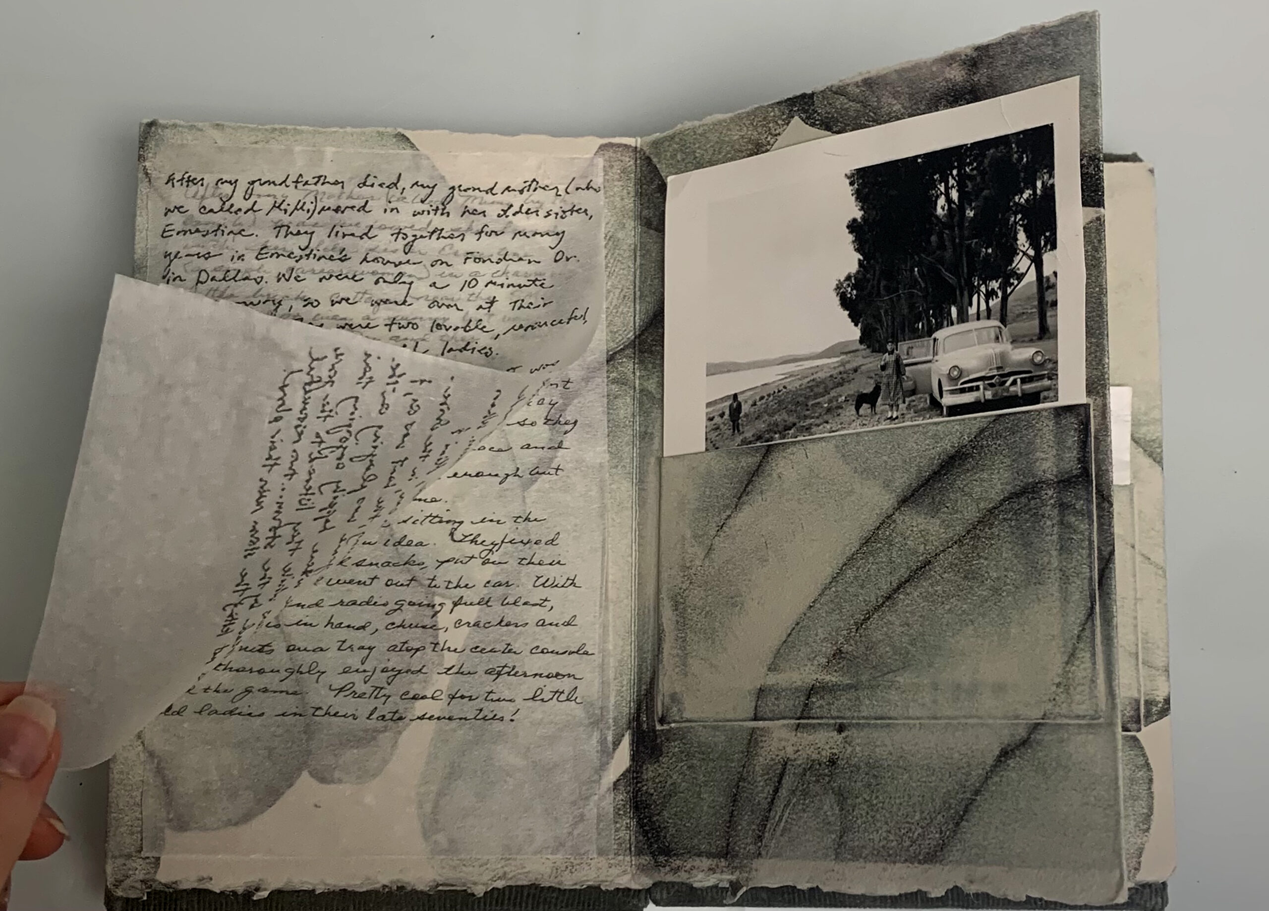 An open page of a green-toned book, with large images of hands abstracting the backgrounds of the pages. On the left-hand side, are two silky pieces of paper with cursive writing laying directly atop one another. On the right-hand side, a black and white photo of a young woman standing by a car peeks out of a small pocket on the page.