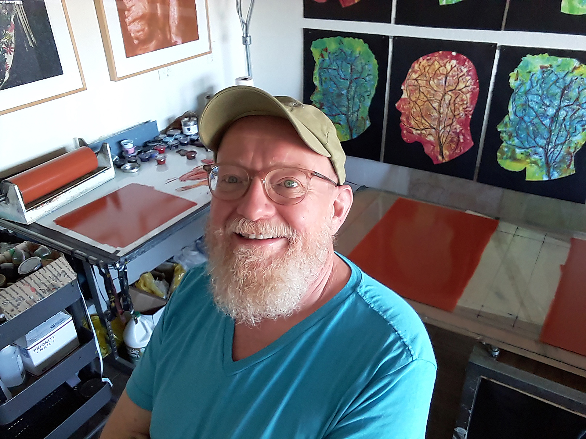 Photograph of a bearded man (the artist) in his studio, surrounded by his work.