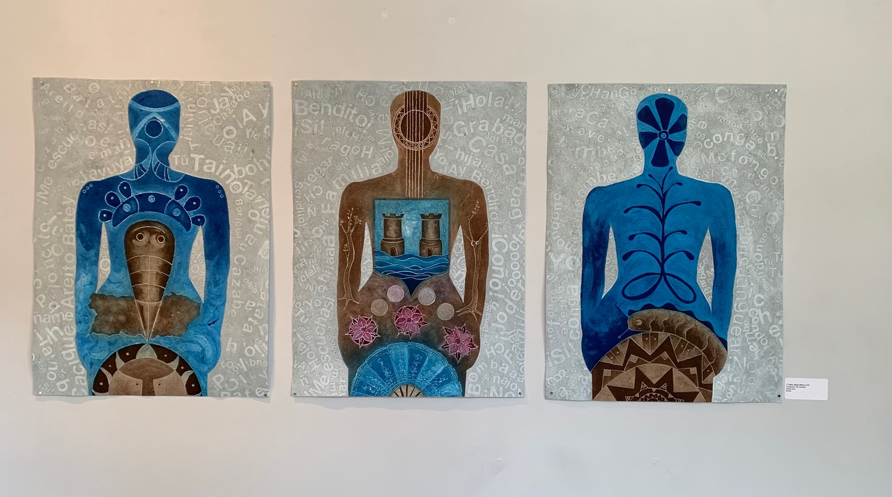 Three abstracted figures stand upon a ground of text in Spanish and Taino. Each figure is filled with imagery, mostly in blues and browns, referencing Taino traditional motifs and colonialism.