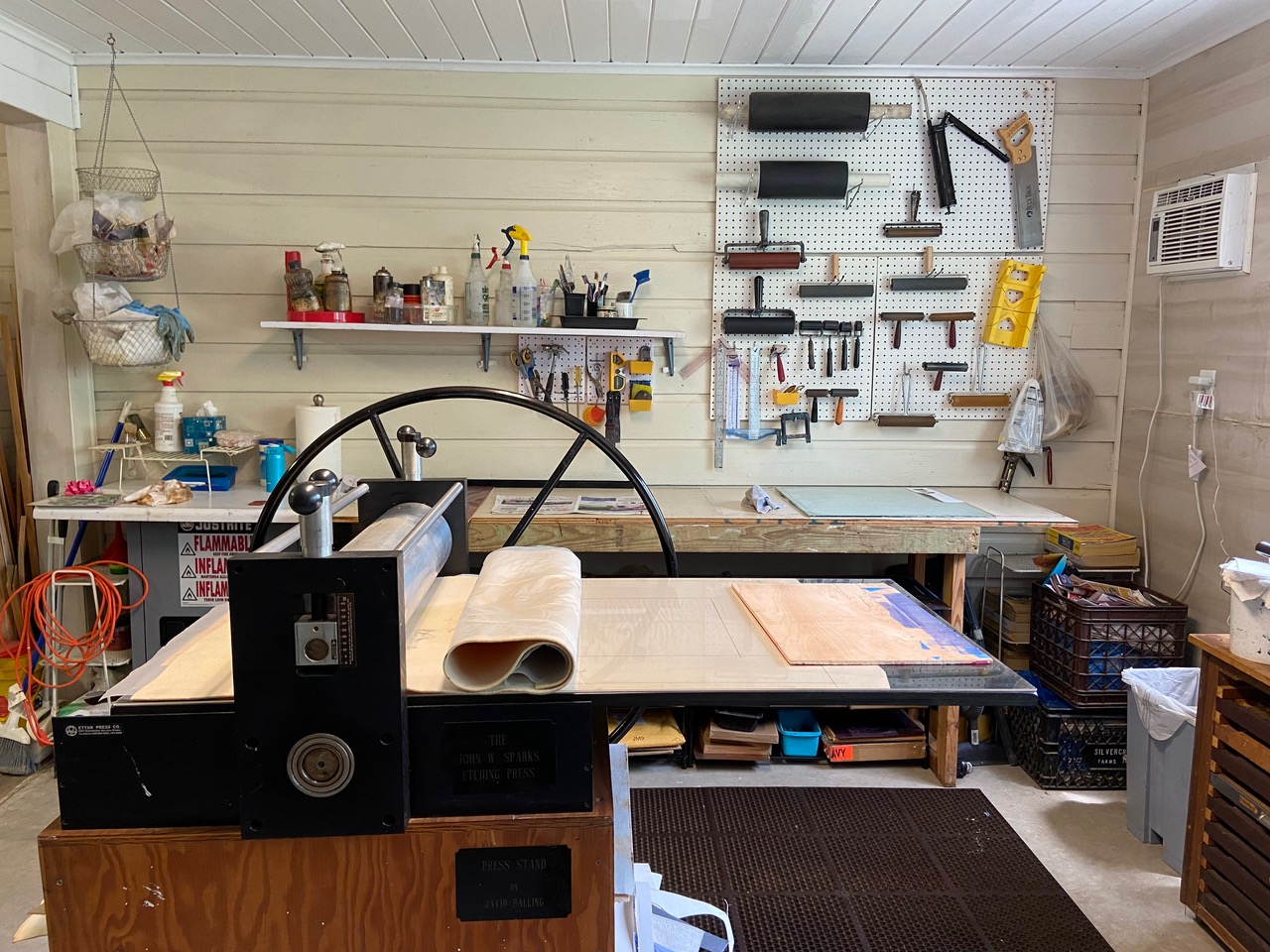 An etching press sits in front of a slab and pegboard workspace at Atabeira Press.