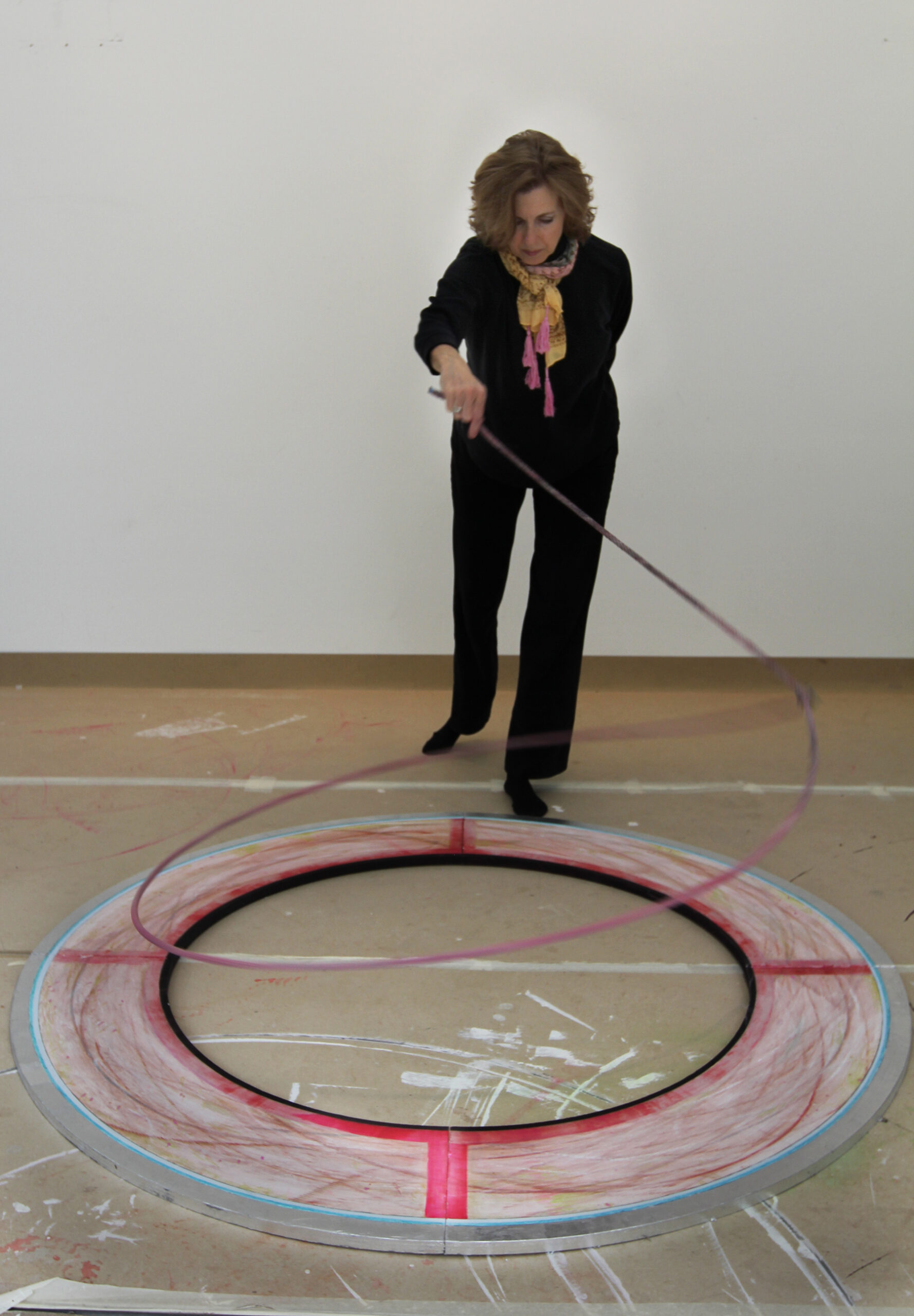 Star Varner roping over a ring sculpture with a bright pink cross. The lasso leaves red marks as it makes contact with the ring, documenting the motion.