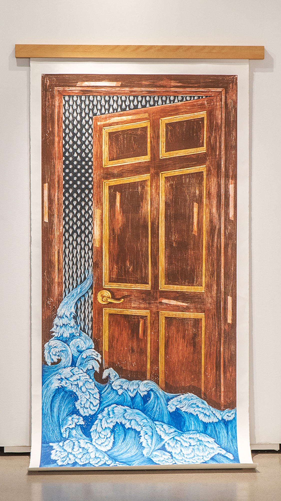 A wooden door ajar, with undulating water flowing out, accompanied by spikes in the door. Created from woodcut print on the paper and hanging on the wall, the piece features blue hues for the water, brown-yellow tones for the door, and grey black for the spikes.