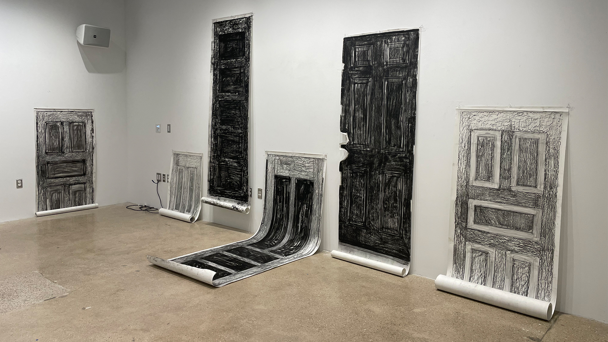 Black and white charcoal five doors rubbings on paper installed at various heights in an installation.