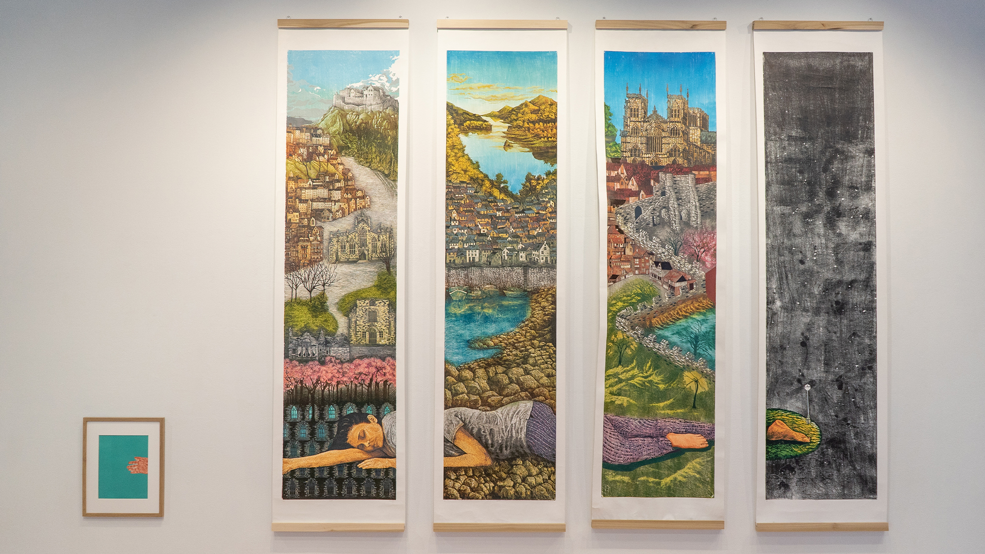 The artist sleeps on the land: a landscape of Edinburgh, Anstruther, Pittenweem, York, and London. The installation features four large woodcut prints on the wall, showcasing 65-85 colors, and a smaller, framed print of a hand.