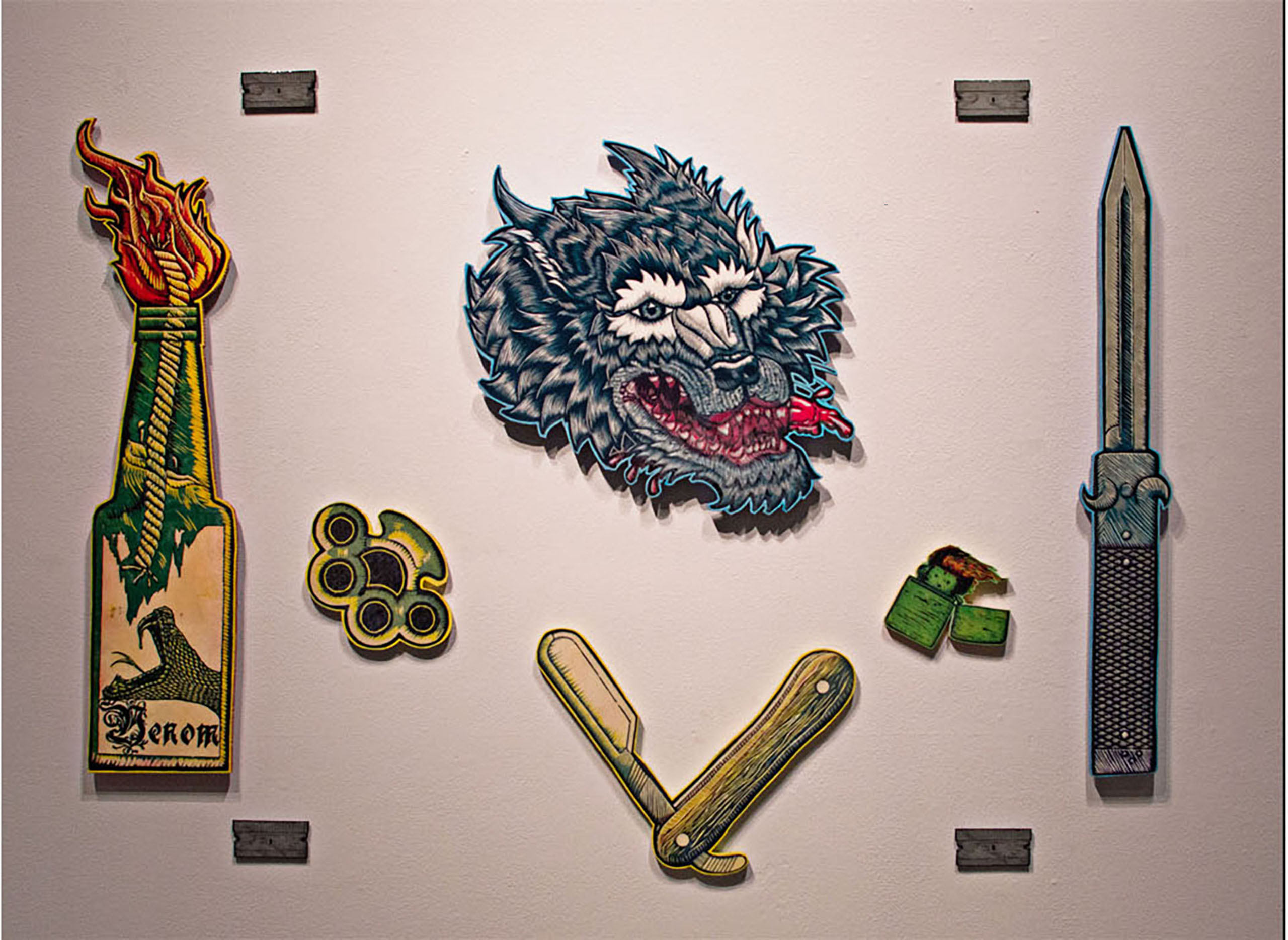 Visible are a wolf head, Molotov cocktail, switchblade, razors, straight razor, brass knuckles and a straight razor.