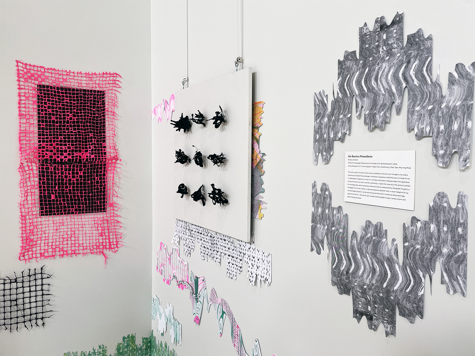 Closeup of a corner installation comprised of handcut riso prints, handmade paper grids, vinyl and a hanging white square with nine 3d marks.