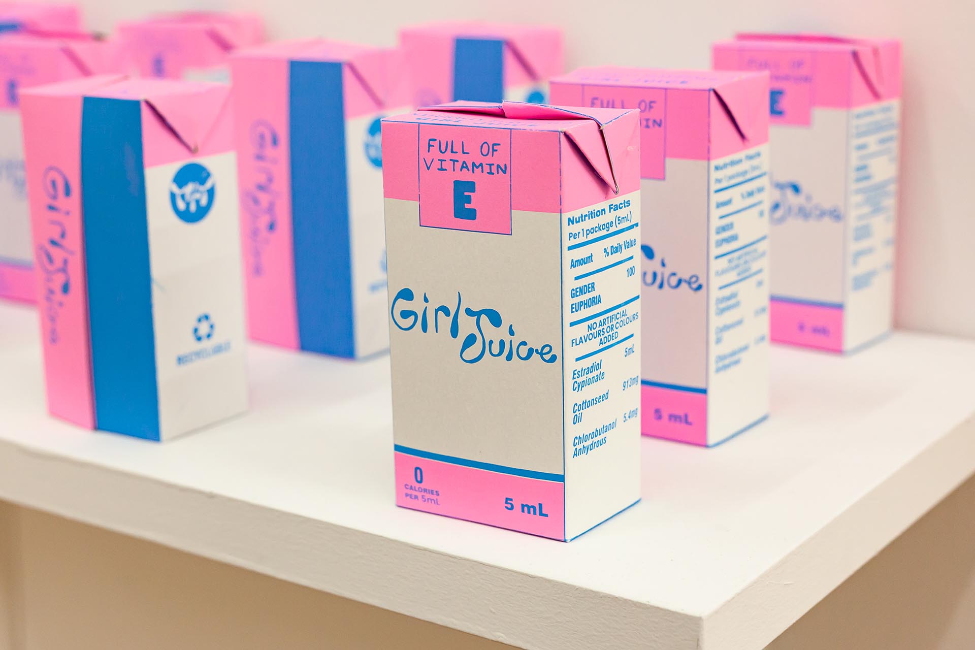 Paper cartons of "Girl Juice", an alternative to typical hormone therapy, printed in a pink motif.