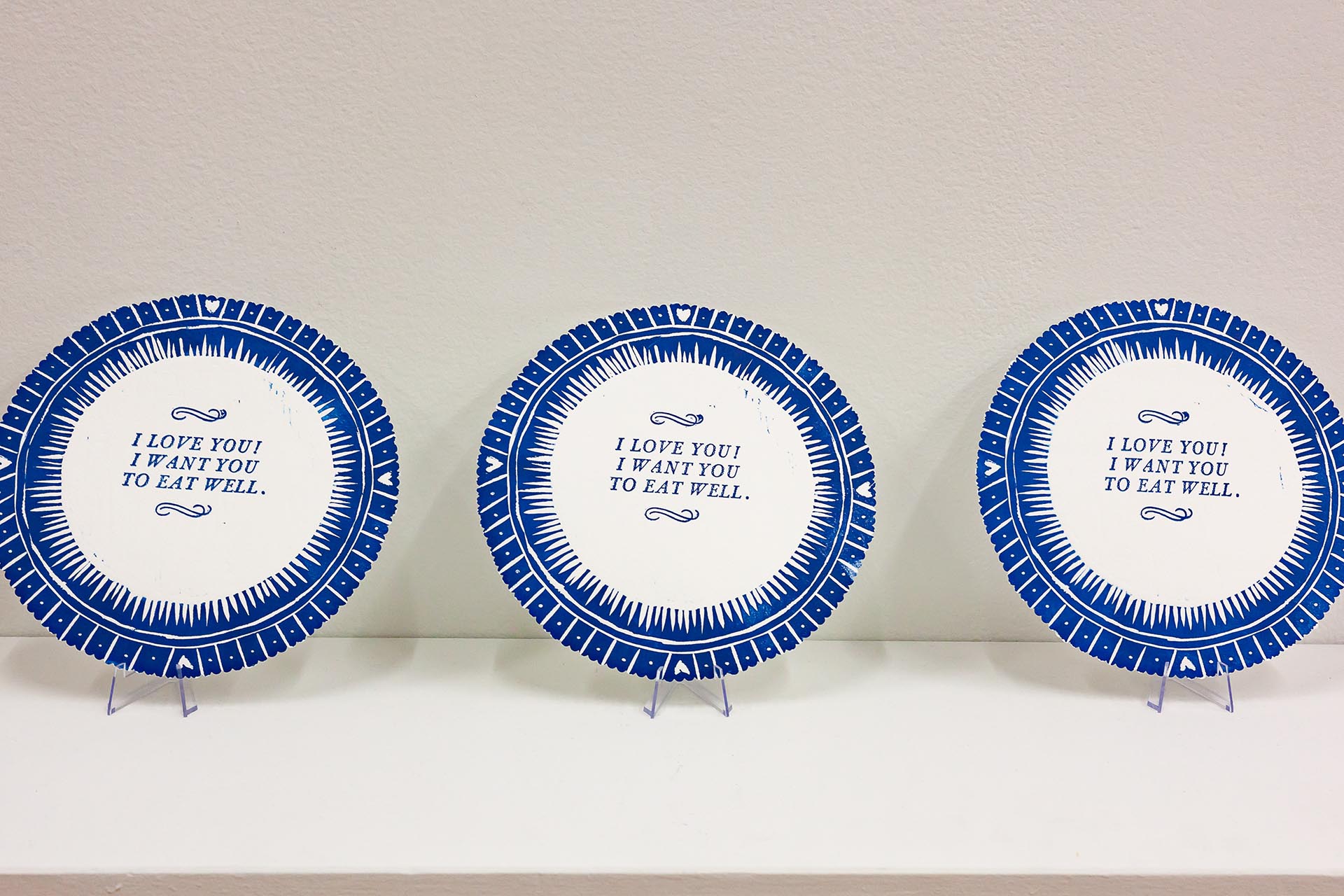 Three paper plates printed with a blue pattern evoking traditional china with the text "I love you! I want you to eat well."