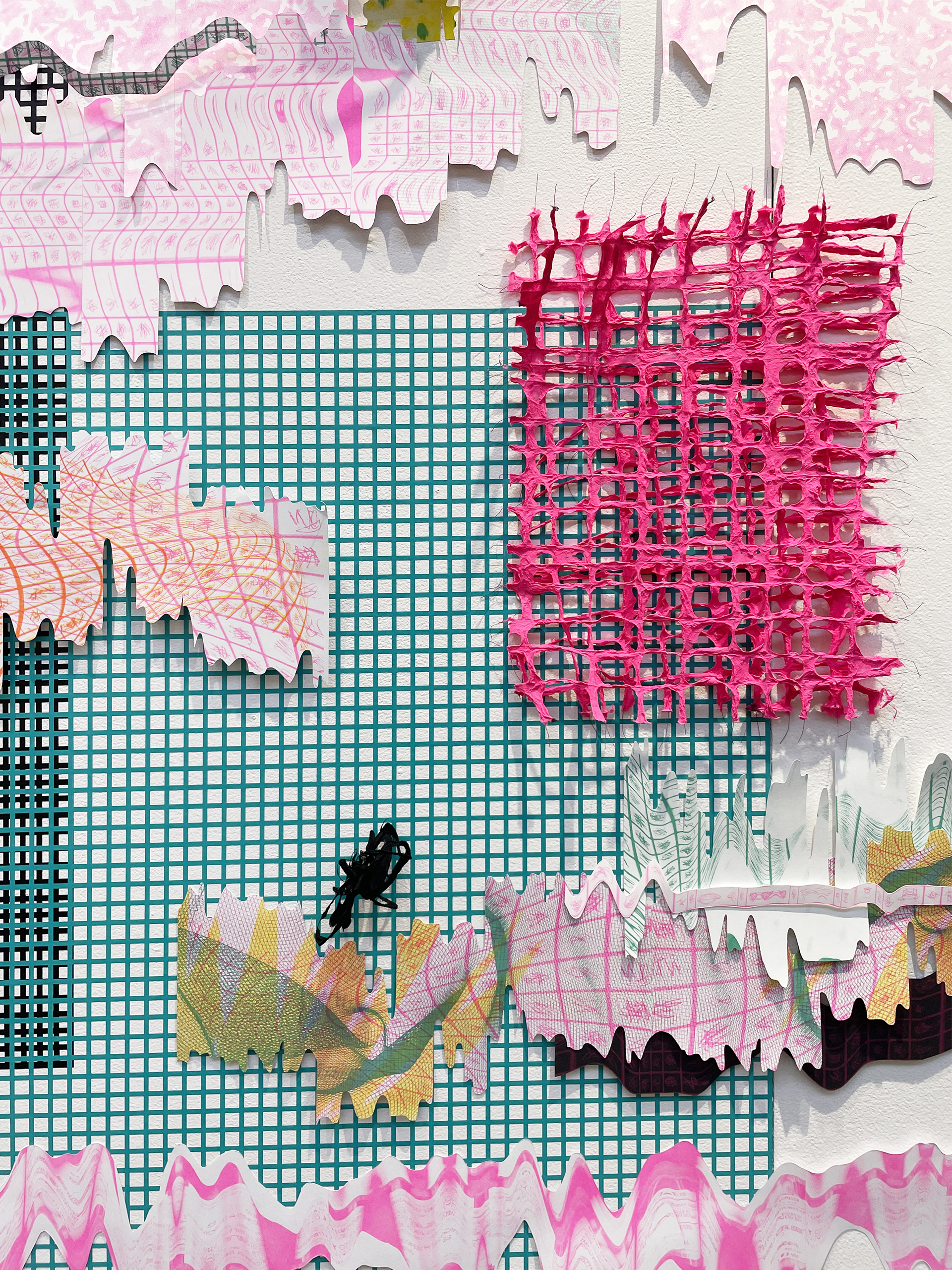 A closeup of a vinyl grid, handmade paper grids in hot pink as well as handcut riso prints along a white wall.