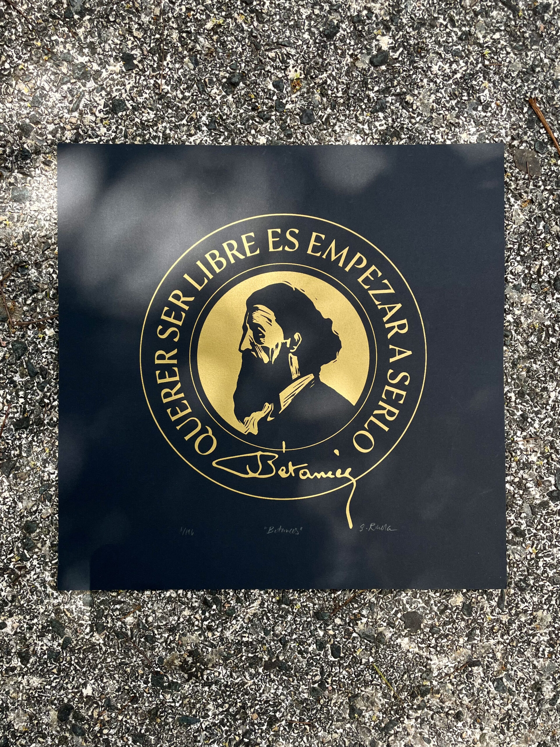 A graphic seal of a man's head in gold ink on a black paper.