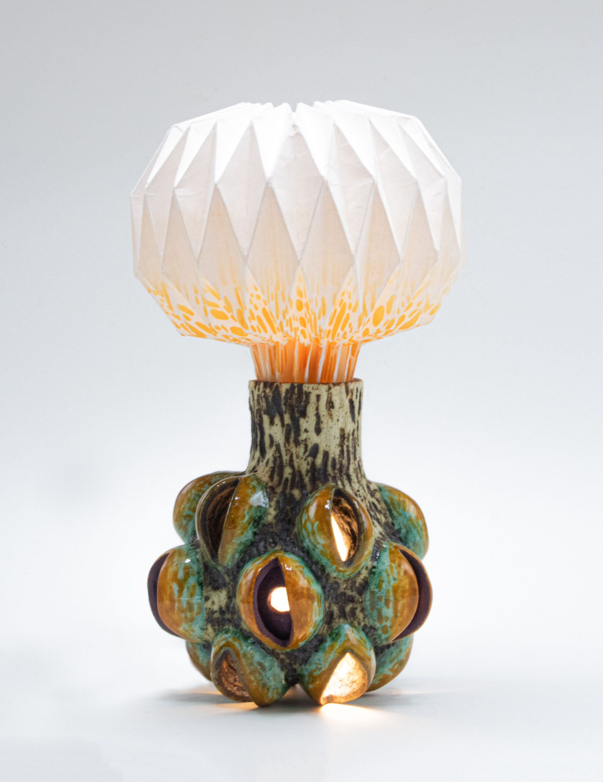 IMG_677 A ceramic form reminiscent of a seed pod with light extending from the seeds has a screenprinted paper plume exploding from the top of the base.