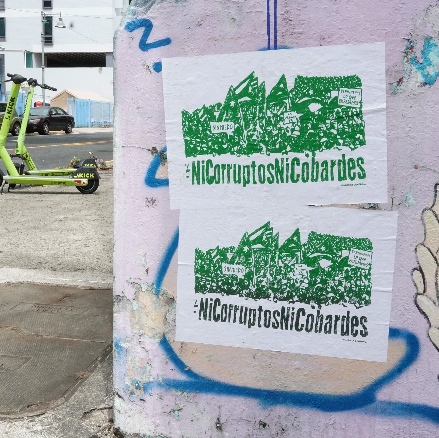 Green screenprints of a protest are wheat pasted on the street.