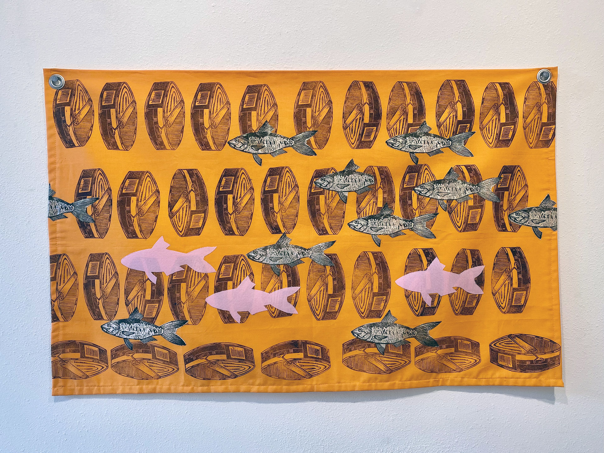 Rows of tuna cans are bisected by swimming fish and pink silhouettes of fish all printed on orange fabric