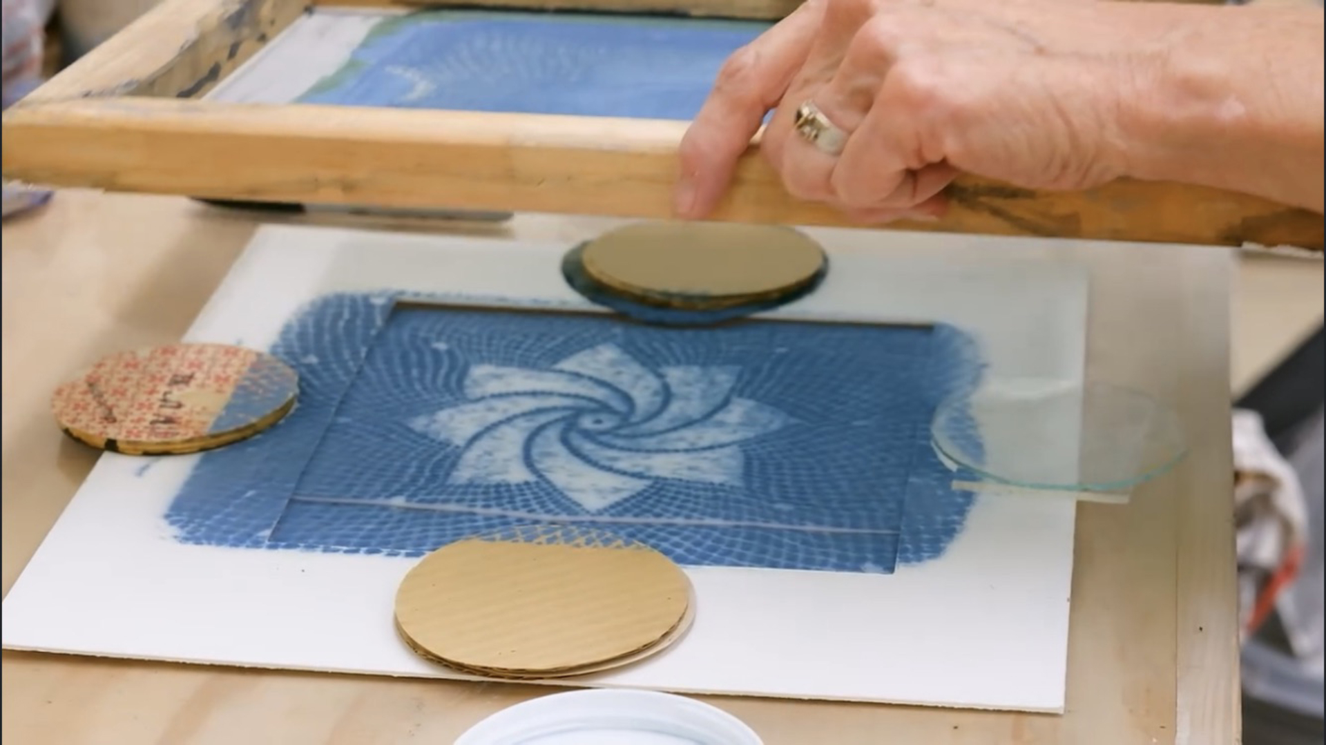 A fluorescent pink abstract shape sits atop a background grid pattern comprised of much smaller abstract scribbled marks in a light teal color.