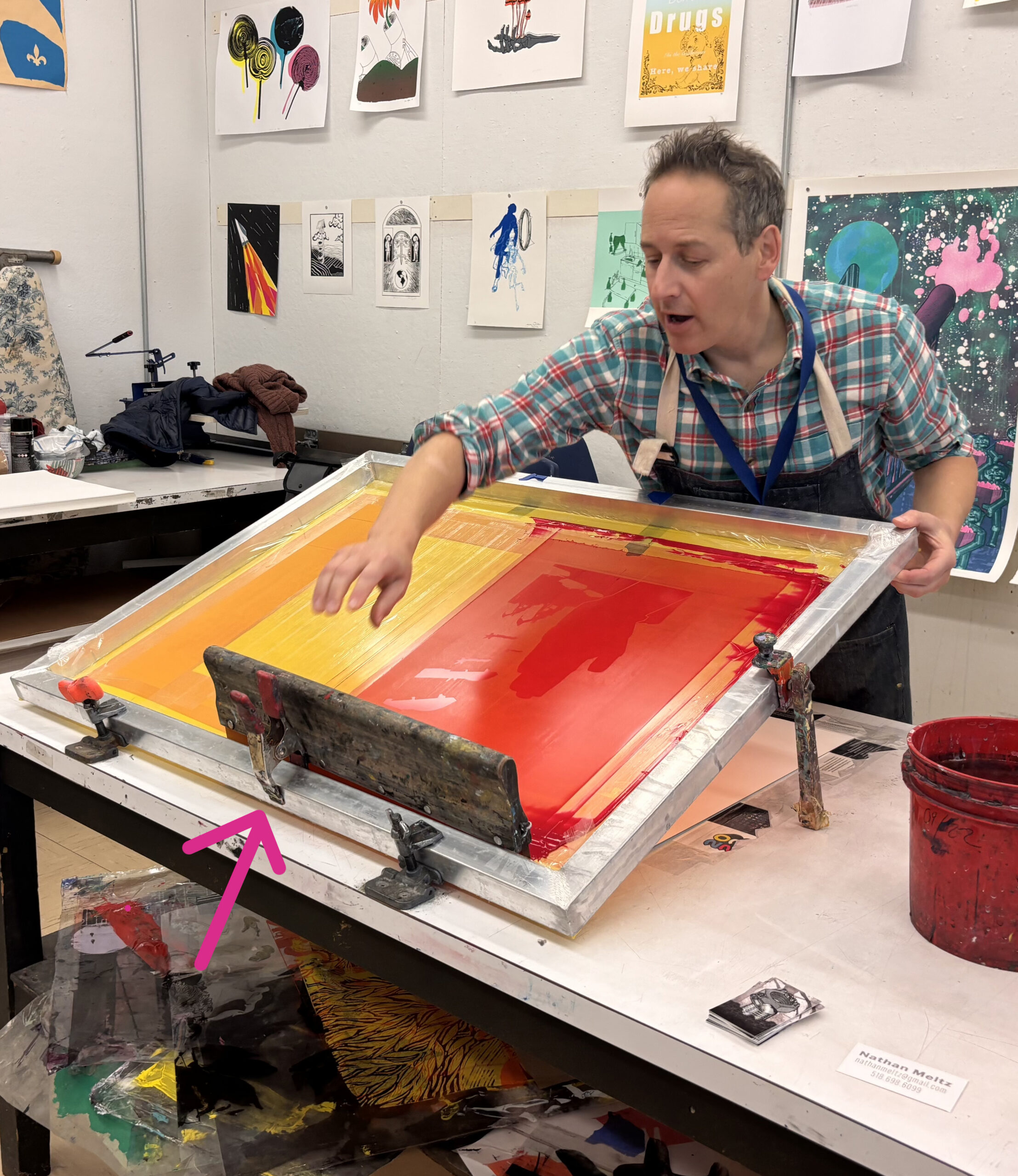 Nathan Meltz pulling a screenprint with a clamp used to brace squeegee when not in use.