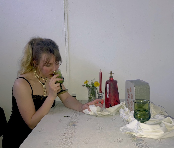 Photo of artist Ellie Westhoff drinking from a goblet at a fancy table